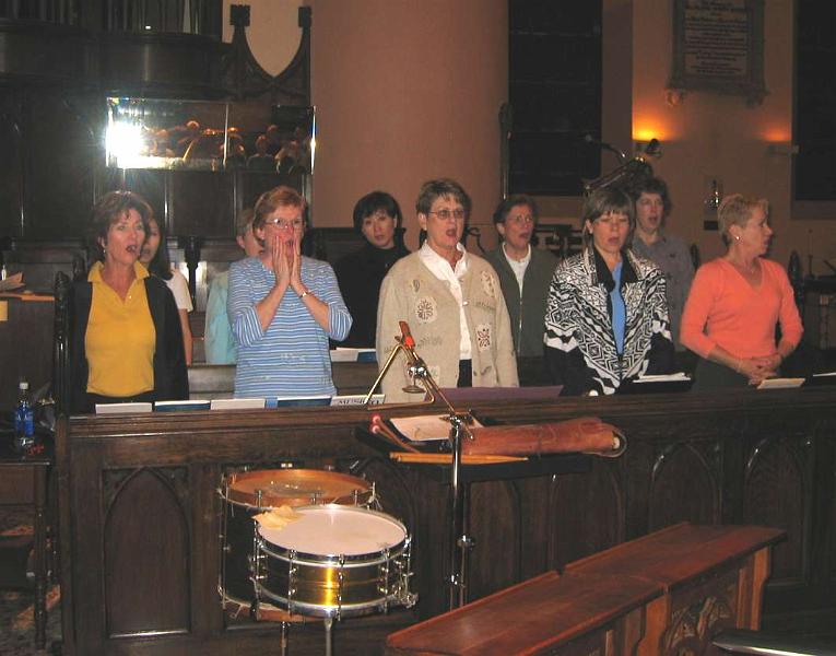 F0058.0010.jpg - Sopranos. 
Everybody is singing nice round notes! From left to right, Marsha, Songyun Park (behind Marsha), Faye (behind Susan), Susan, Jane, Barbara, Rachel, Janice, Mary Beth, and Pam. Songyun is a member of the SFCC.